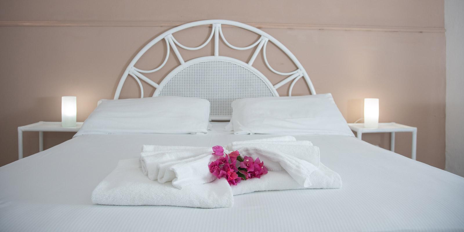 Camera da letto elegante con letto matrimoniale, fiori freschi e illuminazione soffusa.
