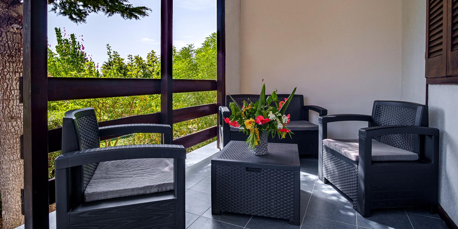 Terrazza con mobili in rattan, fiori colorati e vista sul giardino.
