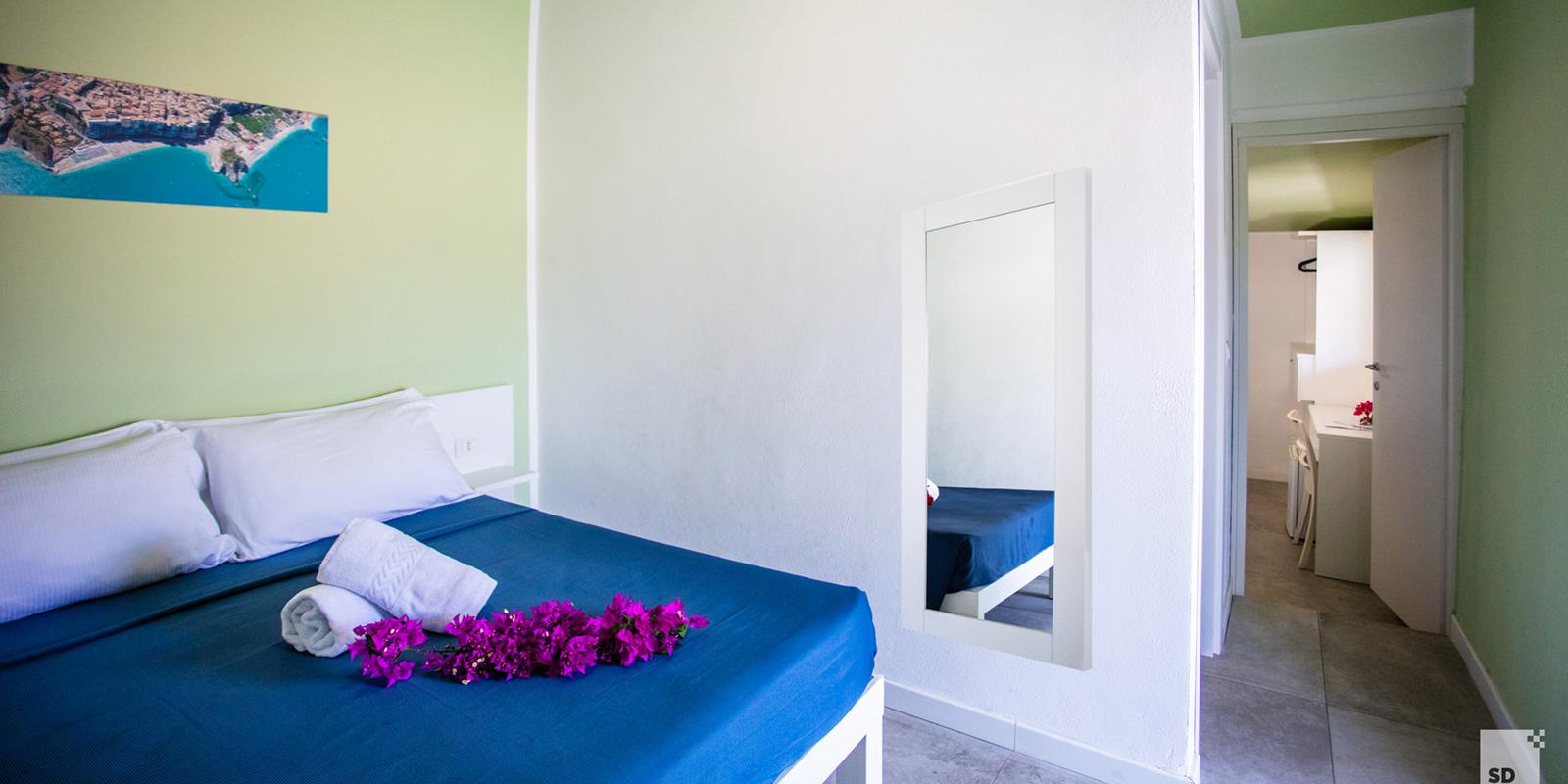 Camera da letto con letto matrimoniale, pareti verde chiaro e decorazioni floreali.