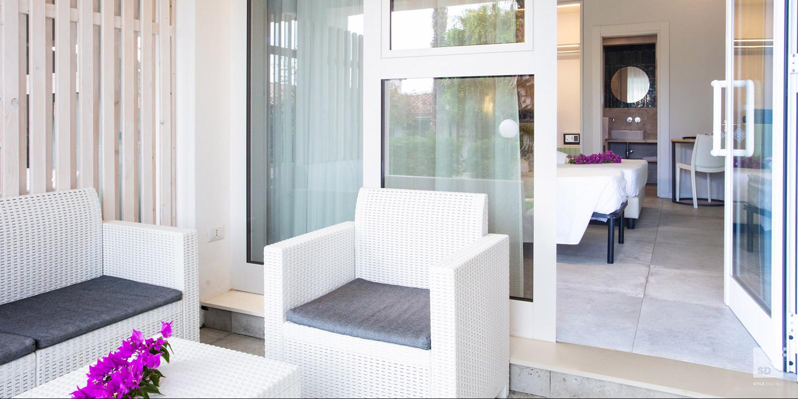Veranda moderna con sedie bianche e vista su una camera elegante.