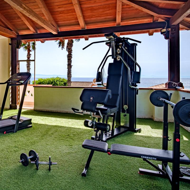 Stabilimento balneare con ombrelloni bianchi su spiaggia e ristorante sopraelevato.